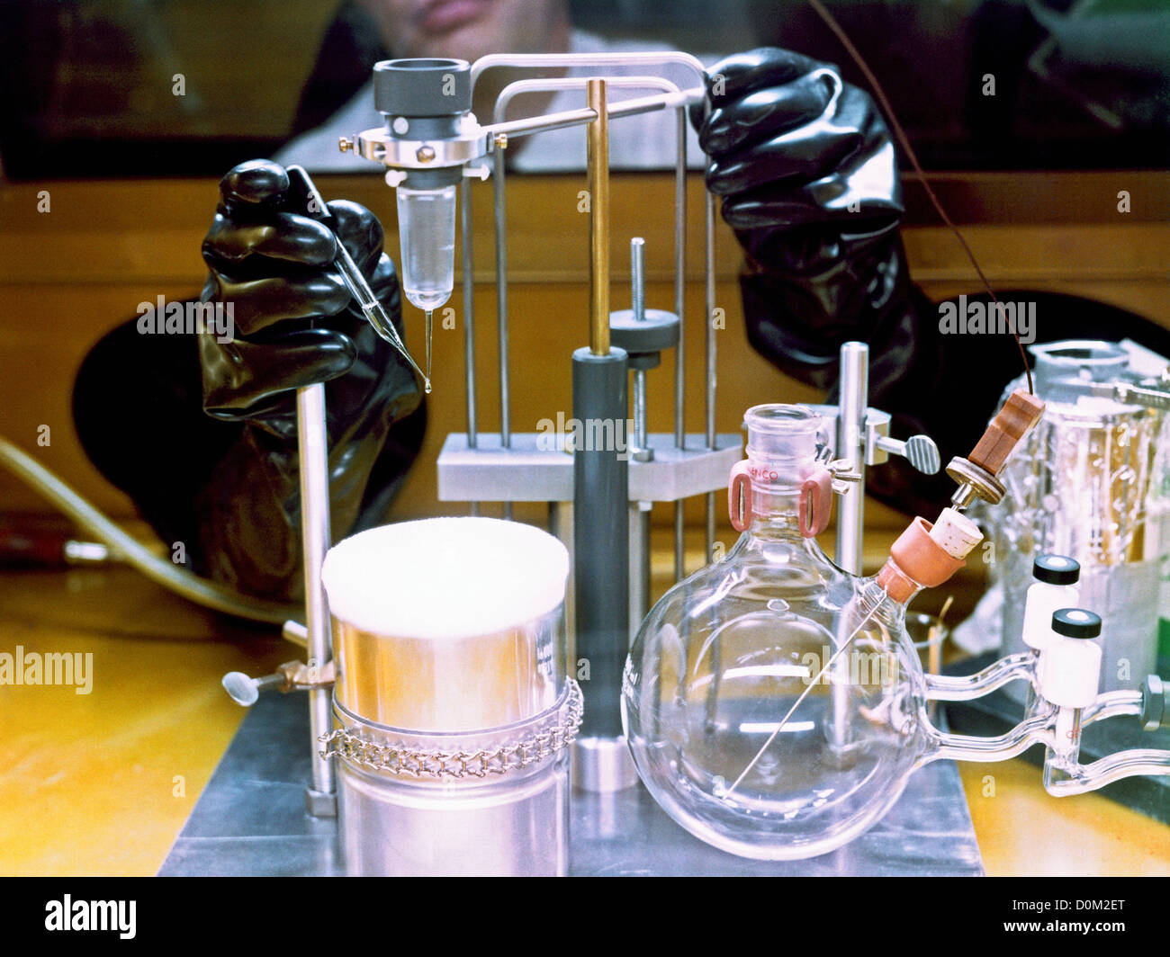 A scientist in a NASA laboratory, circa 1965, uses gloves to work in