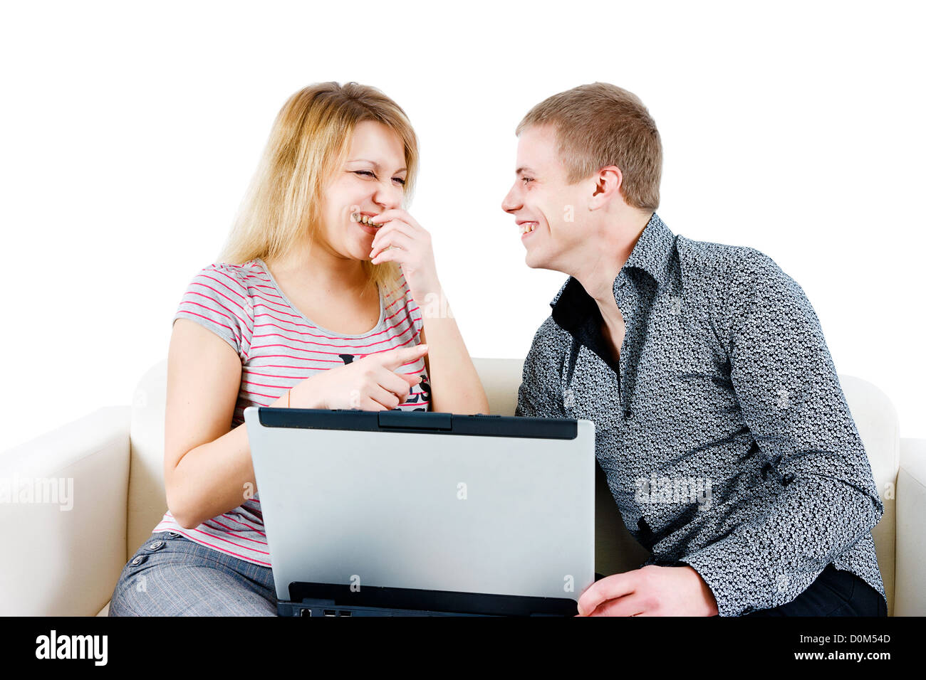 young couple laughing while sitting on the couch with a laptop Stock Photo