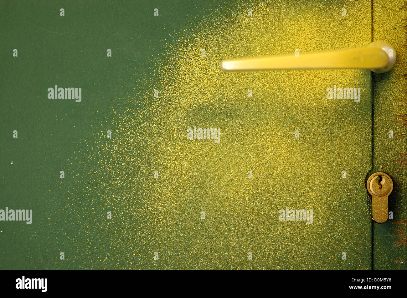 Yellow paint sprayed over green metal door and handle. Abstract background. Stock Photo