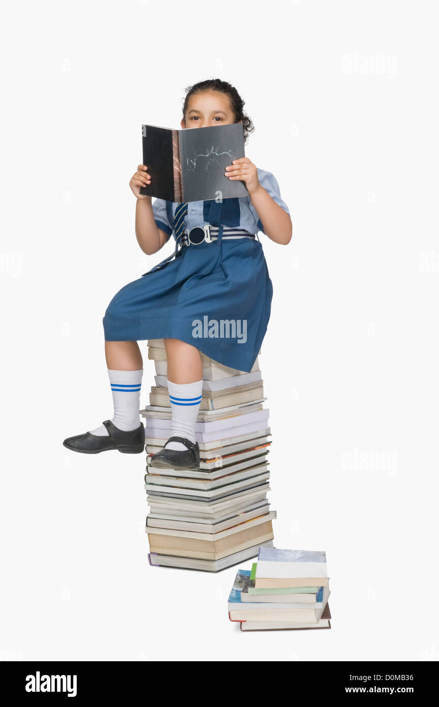 Schoolgirl reading a book on a stack of books Stock Photo - Alamy