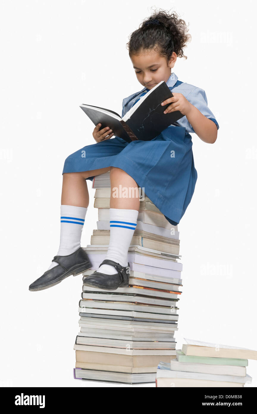 Schoolgirl reading a book on a stack of books Stock Photo - Alamy