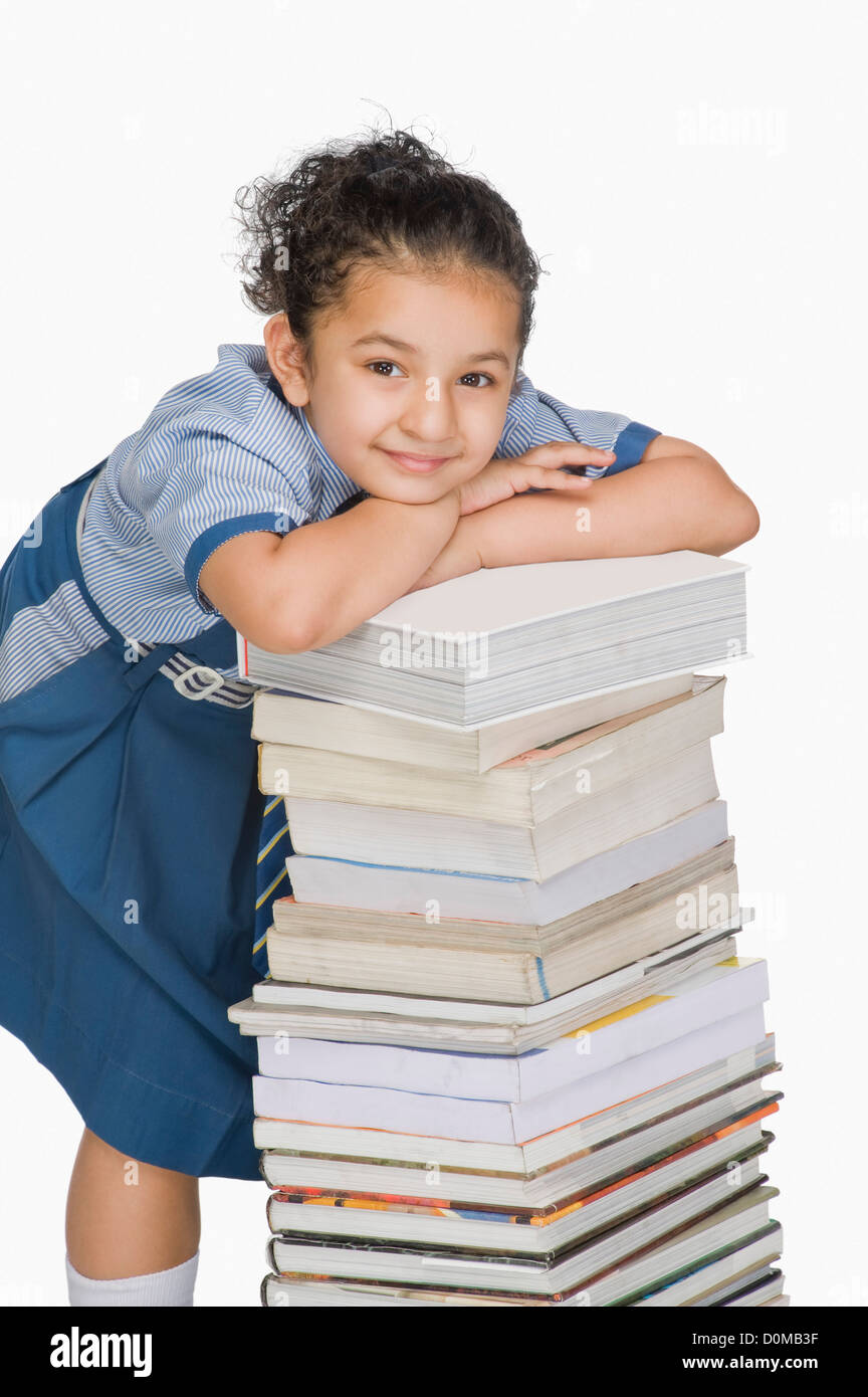 Schoolgirl leaning on a stack of books and smiling Stock Photo - Alamy