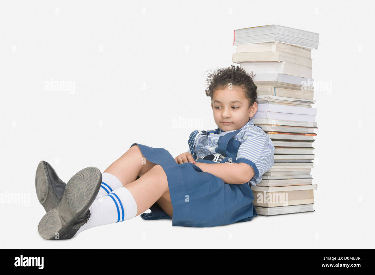 Schoolgirl leaning against a stack of books and looking sad Stock Photo ...