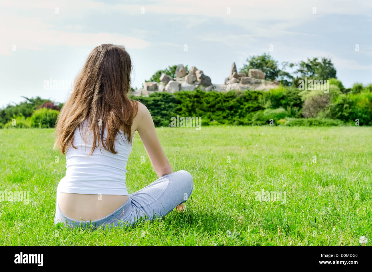 Calm woman sitting on beautiful green lawn on the park Stock Photo