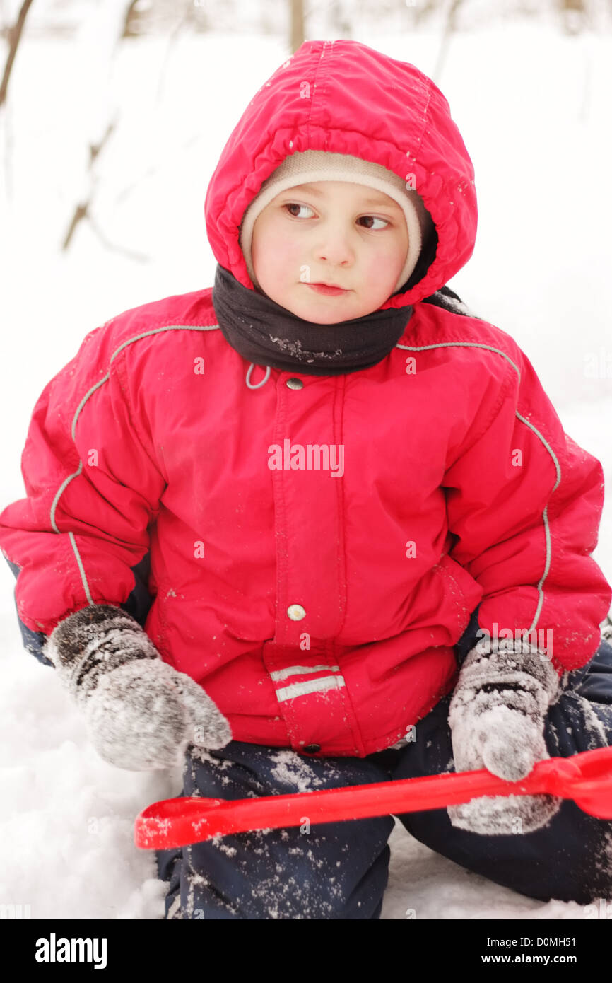 Little kid in red jacket sitting with shovel Stock Photo Alamy