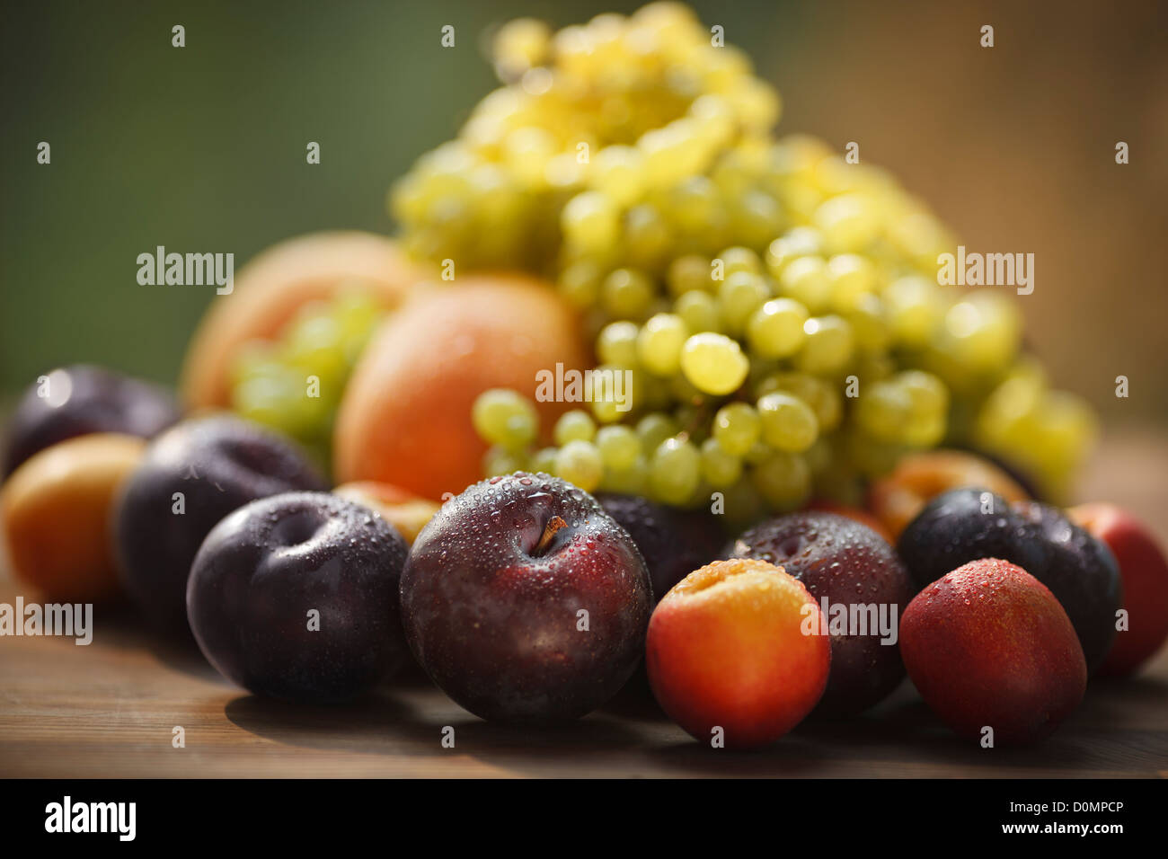 still life with fresh and wet fruits, selective focus on nearest plum ...