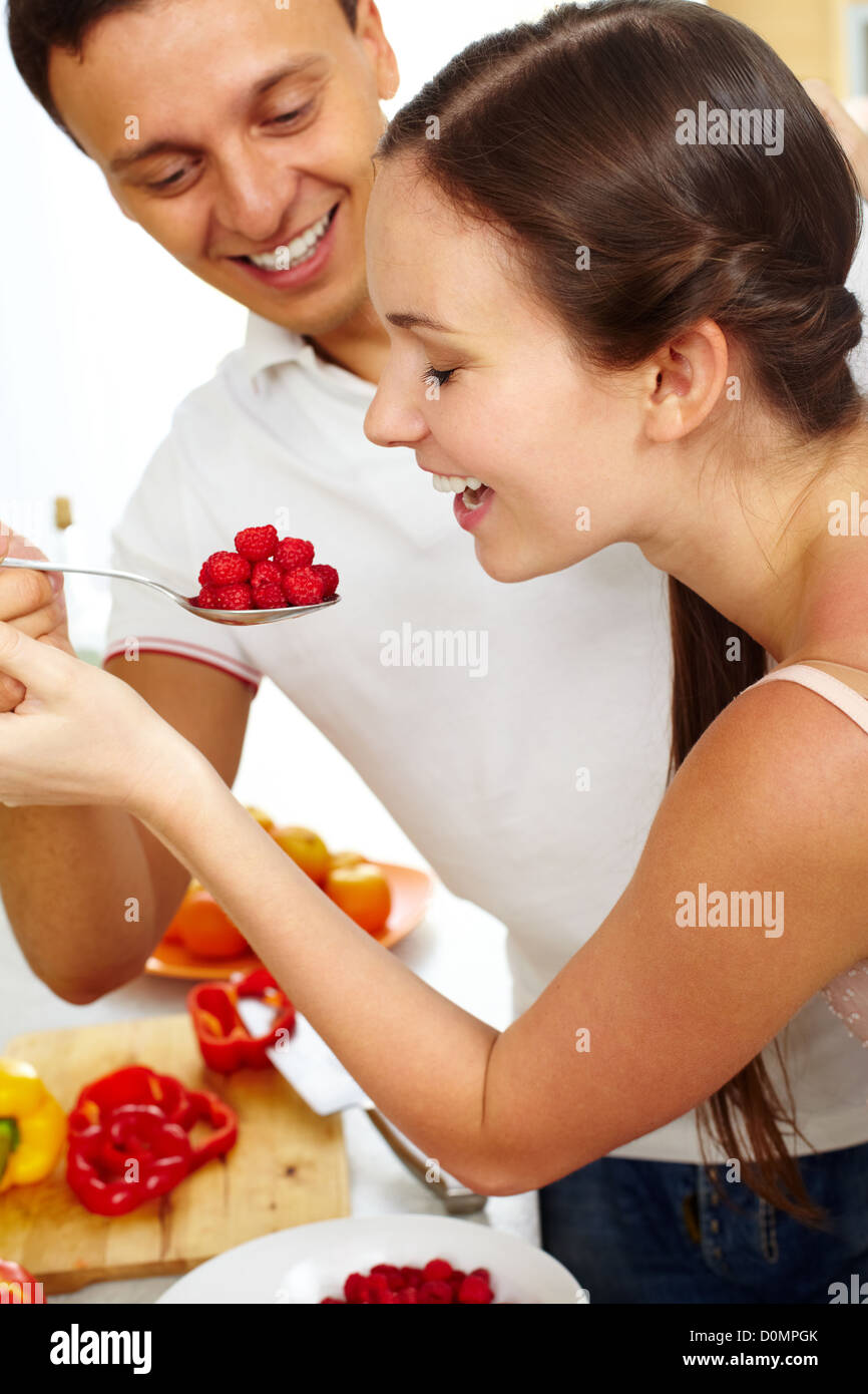 Young man feeding happy woman with ripe raspberry Stock Photo