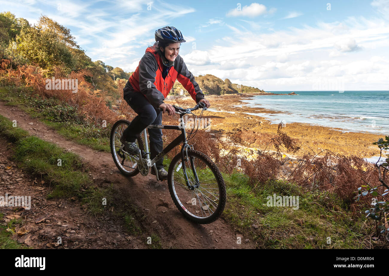 Female cyclist on coast path mountain biking, St Catherine's, Jersey east coast, Channel Islands, UK Stock Photo