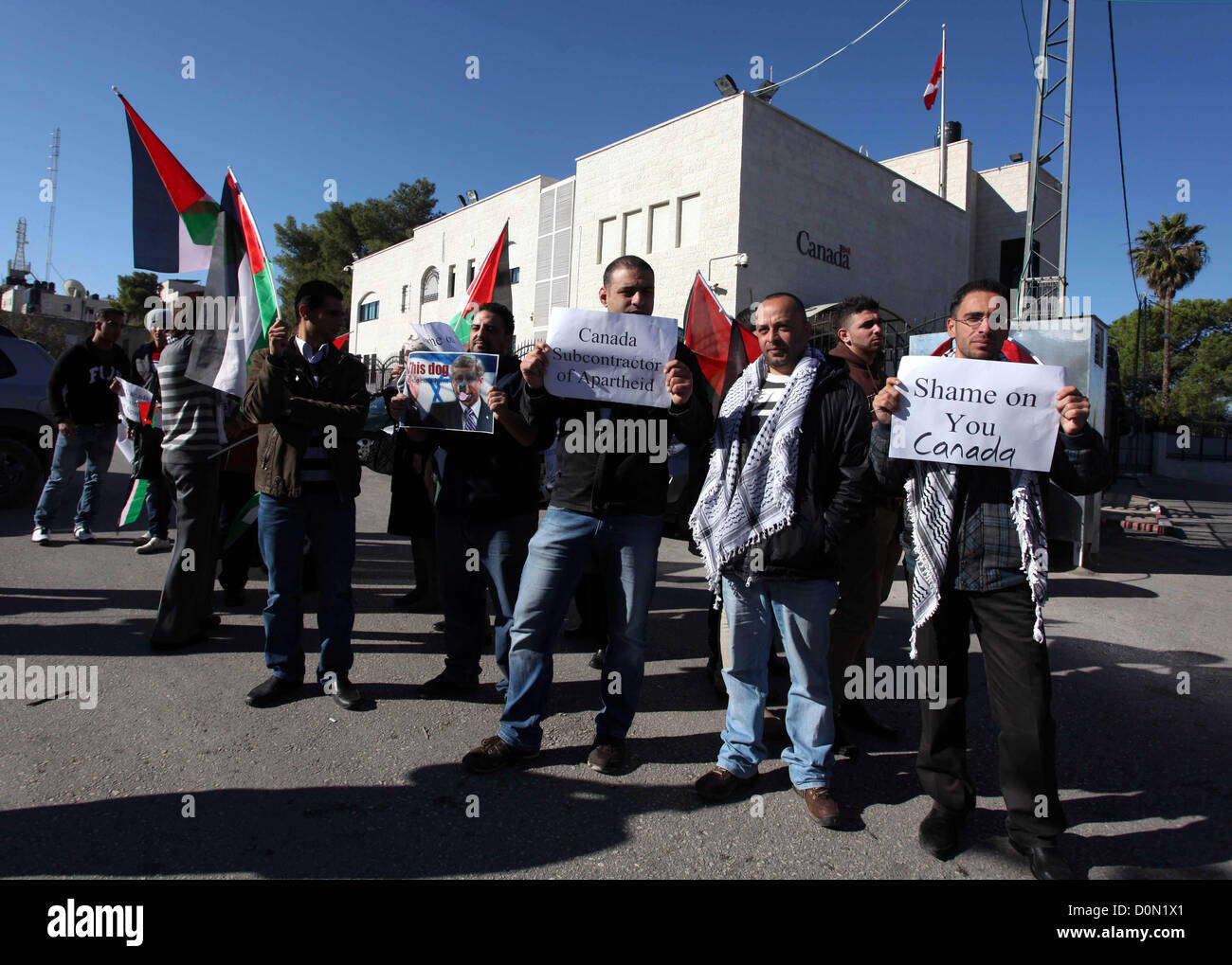 Nov. 28, 2012 - Ramallah, West Bank, Palestinian Territory - Palestinians hold national flags and a poster of Canadian Prime Minister Stephen Harper superimposed with a face of a dog during a protest following his remarks about the Palestinian UN bid for an observer state status, in front of Canadian representative offices in the West bank city of Ramallah, Wednesday, Nov. 28, 2012. Harper has threatened ''there will be consequences'' if Palestinian Authority President Mahmoud Abbas does not end his campaign for the Palestinian Authority to be recognized by the UN as a non-member observer stat Stock Photo