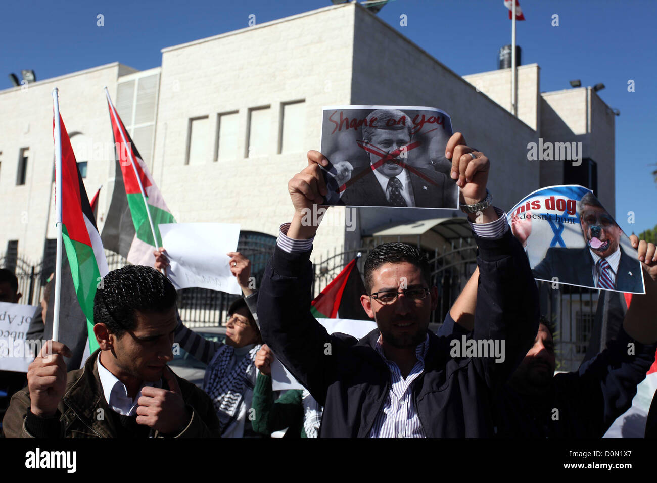 Nov. 28, 2012 - Ramallah, West Bank, Palestinian Territory - Palestinians hold national flags and a poster of Canadian Prime Minister Stephen Harper superimposed with a face of a dog during a protest following his remarks about the Palestinian UN bid for an observer state status, in front of Canadian representative offices in the West bank city of Ramallah, Wednesday, Nov. 28, 2012. Harper has threatened ''there will be consequences'' if Palestinian Authority President Mahmoud Abbas does not end his campaign for the Palestinian Authority to be recognized by the UN as a non-member observer stat Stock Photo