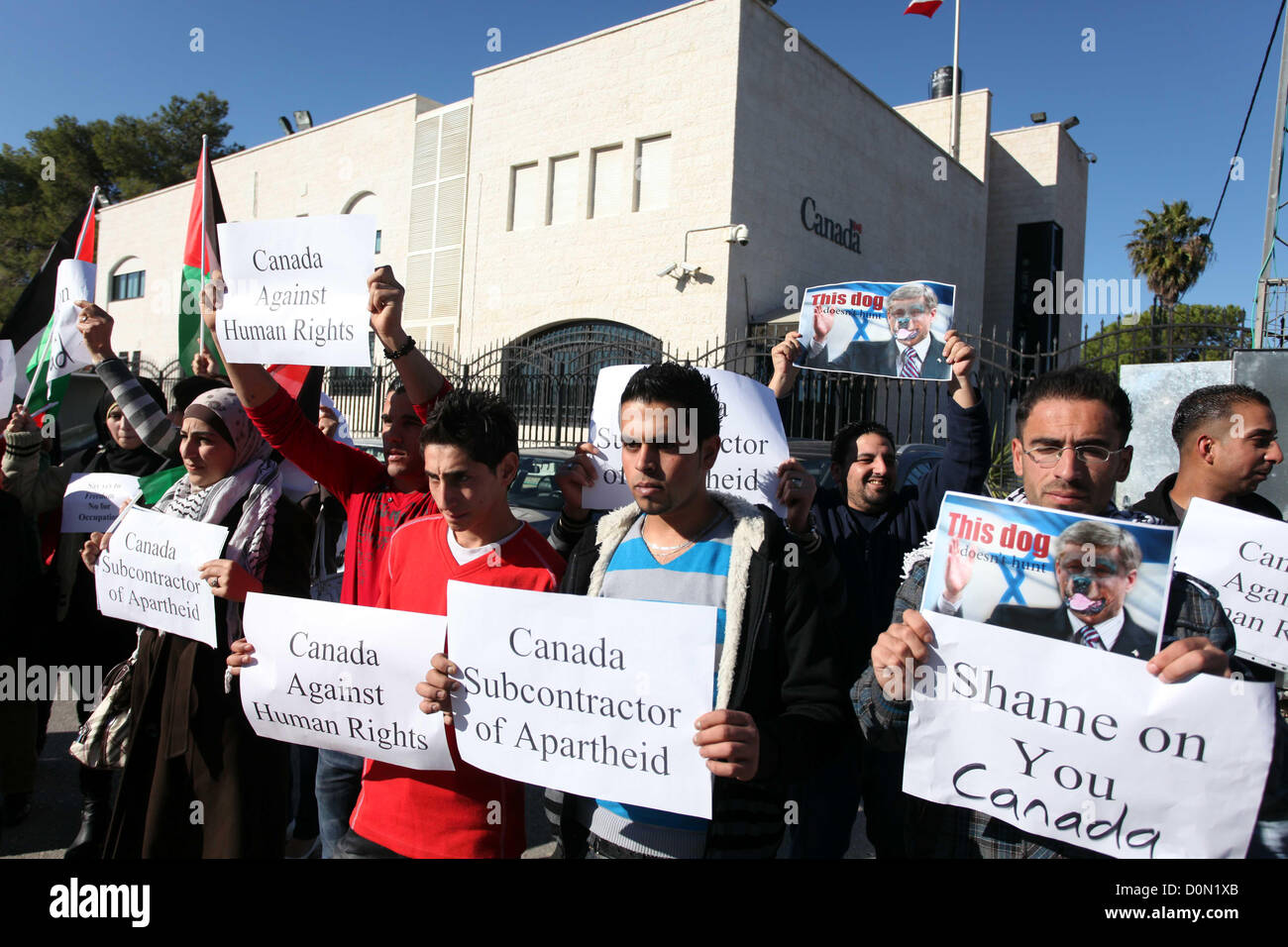 Nov. 28, 2012 - Ramallah, West Bank, Palestinian Territory - Palestinians hold national flags and a poster of Canadian Prime Minister Stephen Harper superimposed with a face of a dog during a protest following his remarks about the Palestinian UN bid for an observer state status, in front of Canadian representative offices in the West bank city of Ramallah, Wednesday, Nov. 28, 2012. Harper has threatened ''there will be consequences'' if Palestinian Authority President Mahmoud Abbas does not end his campaign for the Palestinian Authority to be recognized by the UN as a non-member observer stat Stock Photo