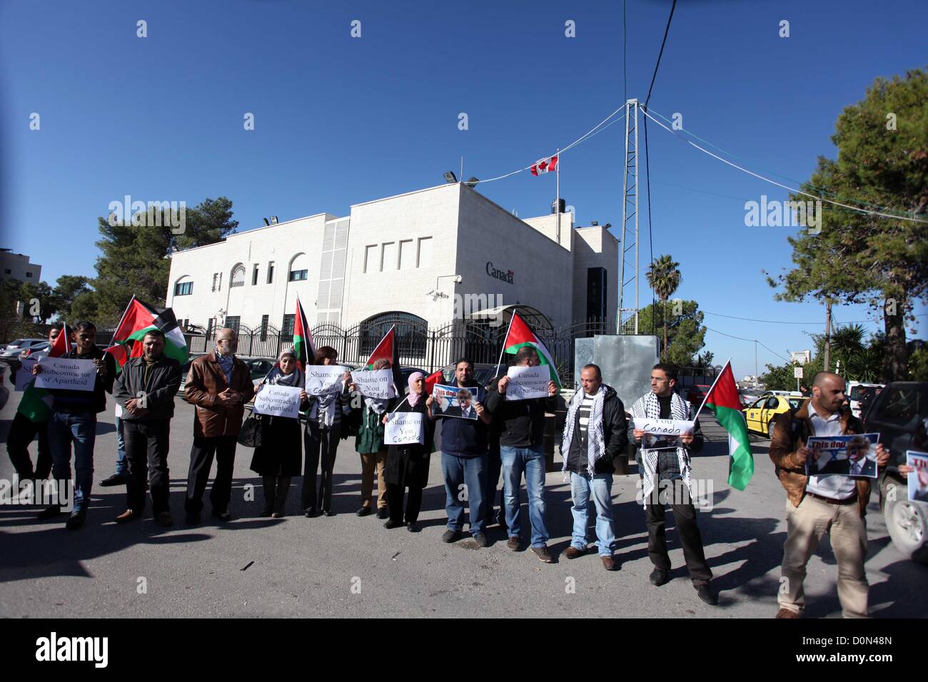 Nov. 28, 2012 - Ramallah, West Bank, Palestinian Territory - Palestinians hold national flags and a poster of Canadian Prime Minister Stephen Harper superimposed with a face of a dog during a protest following his remarks about the Palestinian UN bid for an observer state status, in front of Canadian representative offices in the West bank city of Ramallah, Wednesday, Nov. 28, 2012. Harper has threatened ''there will be consequences'' if Palestinian Authority President Mahmoud Abbas does not end his campaign for the Palestinian Authority to be recognized by the UN as a non-member observer stat Stock Photo