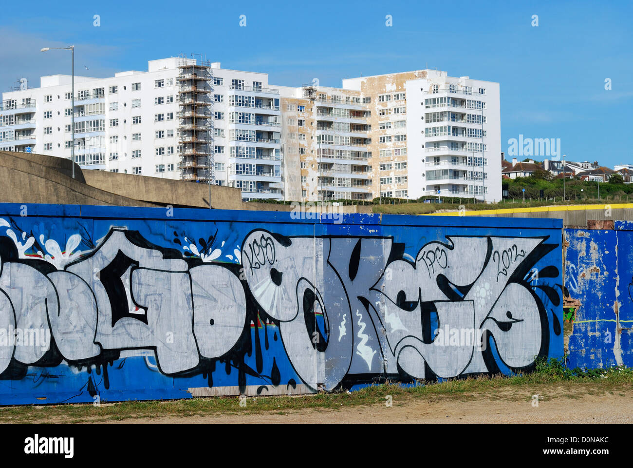 Graffiti on wall near Marina with block of flats being repainted in background. Brighton. East Sussex. England Stock Photo
