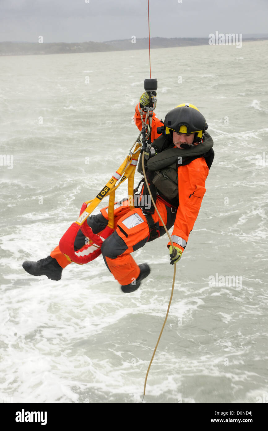 A coastguard helicopter winchman is lowered to a boat on a stormy day Stock Photo Alamy