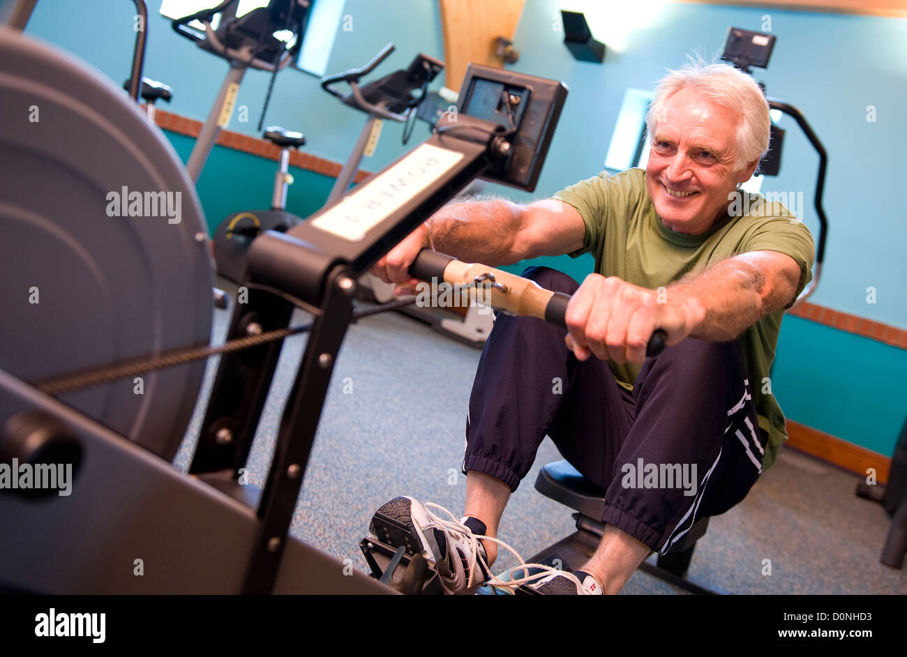 senior male using rowing machine in gym Stock Photo