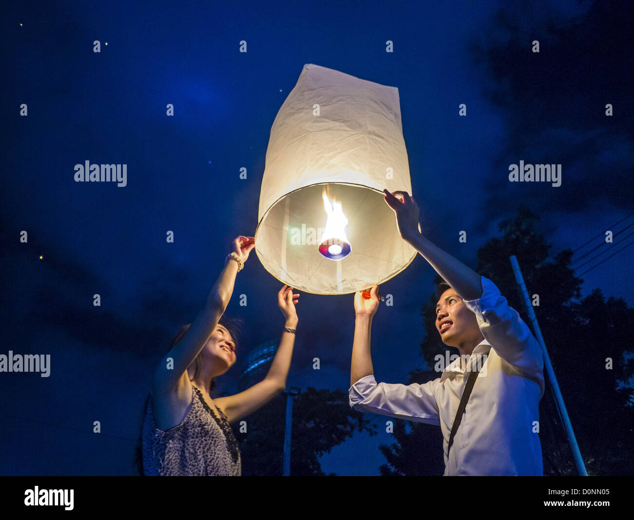 Nov. 28, 2012 - Bangkok, Thailand - People try to light a Khom Loi lantern  during Loy Krathong at Wat Yannawa. The lanterns are a part of the Loy Krathong tradition in northern Thailand, and are becoming popular in Bangkok. Authorities don't allow their use in Bangkok because of the fire danger. They try to stop people from launching the lanterns in Bangkok. (Credit Image: © Jack Kurtz/ZUMAPRESS.com) Stock Photo