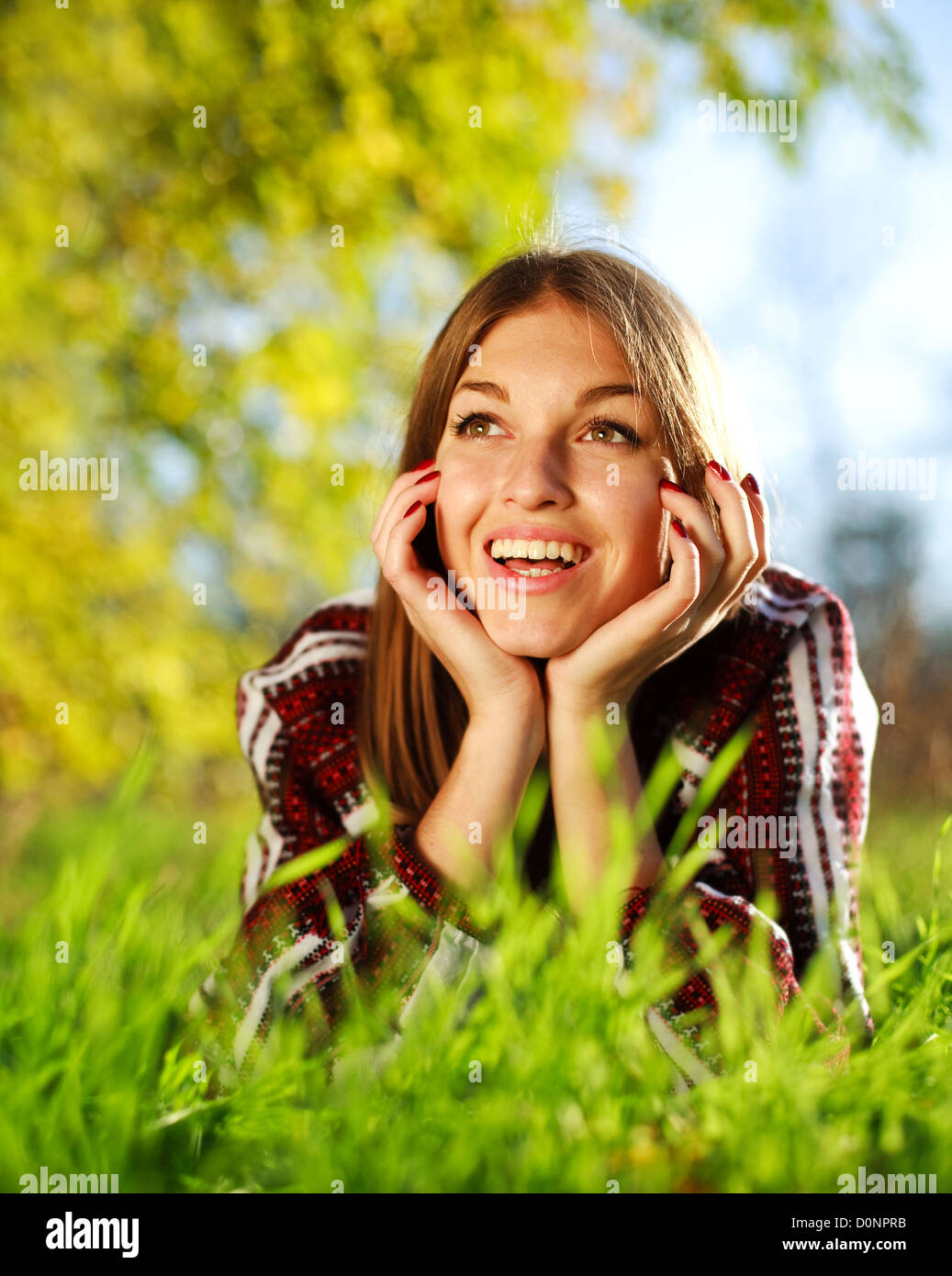Pretty joyful young girl lying on green grass close up,in summer park. Stock Photo