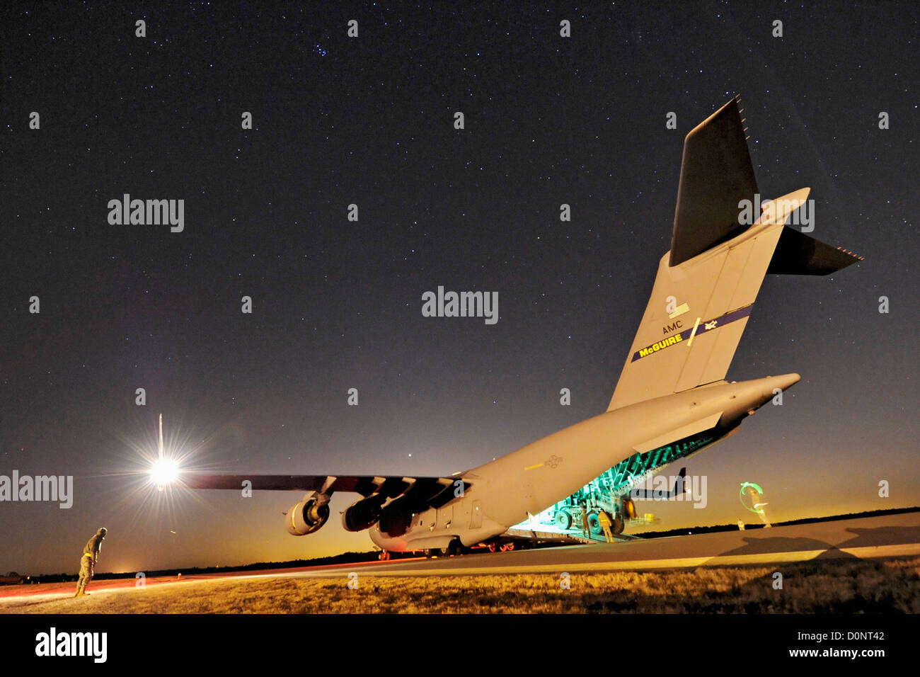 Aerial porters 621st Contingency Response Wing guide articulated forklift C-17 Globemaster III during nighttime engine-running Stock Photo