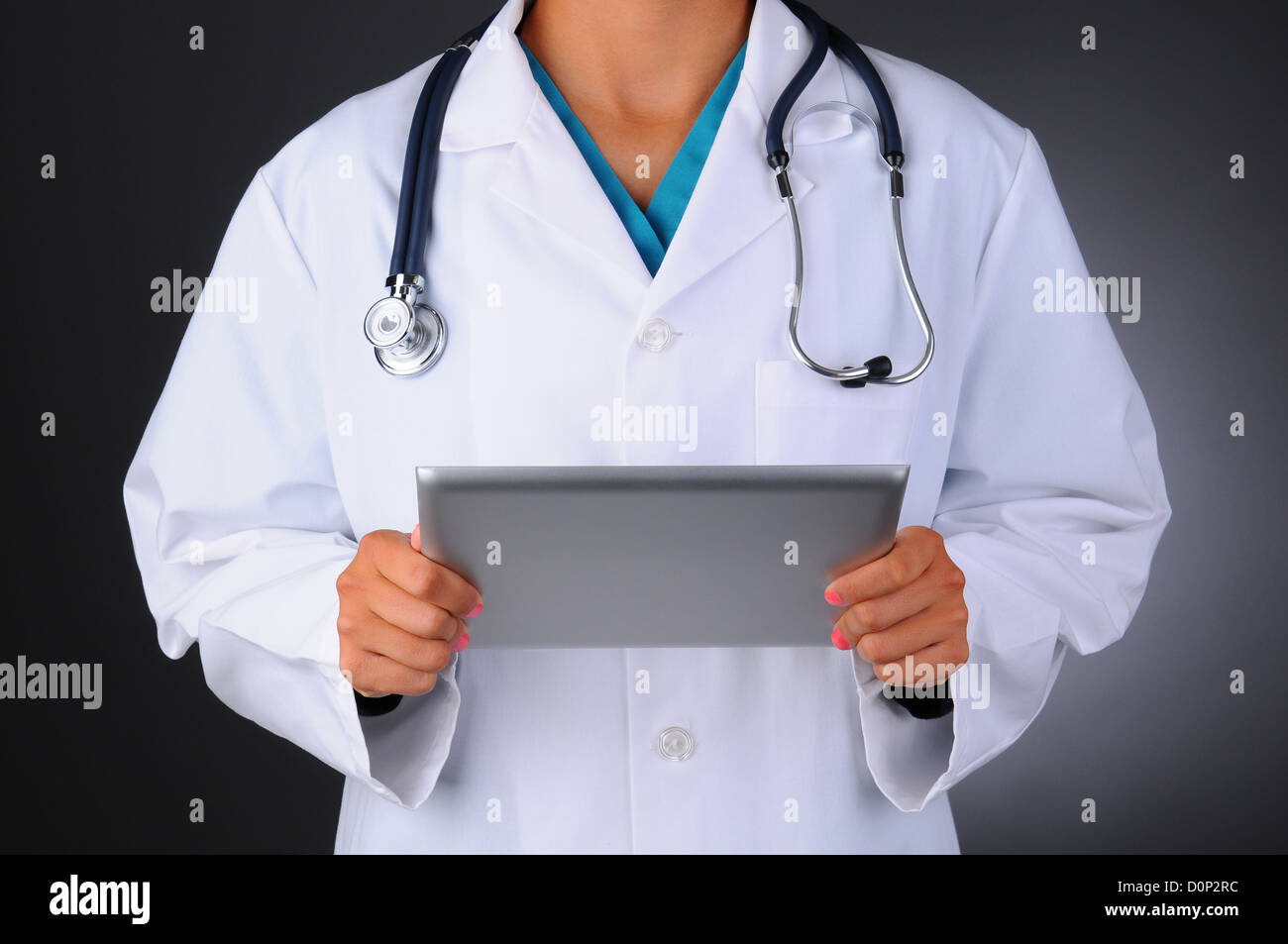 Closeup of a female medical professional wearing scrubs and lab coat holding a tablet computer. Stock Photo