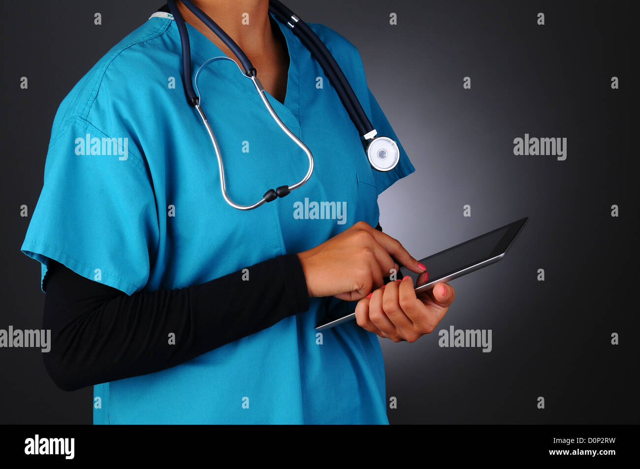 Closeup of a female medical professional wearing scrubs taking notes on a tablet computer. Stock Photo