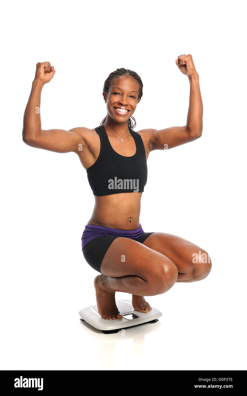 African American woman celebrating weight loss standing on scale Stock Photo
