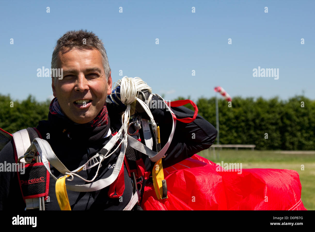Man over 55 years is smiling after a save parachute landing. He's happy that he found a new sport for a good Work-Live balance. Stock Photo