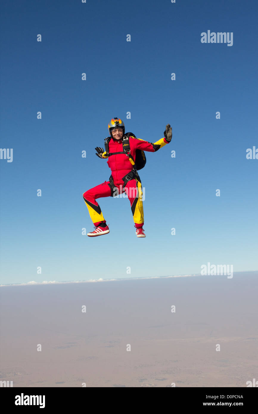 Skydiver is flying free over the Dubai desert and performance a sit fly move. The scenery is perfect from this hight in the sky. Stock Photo