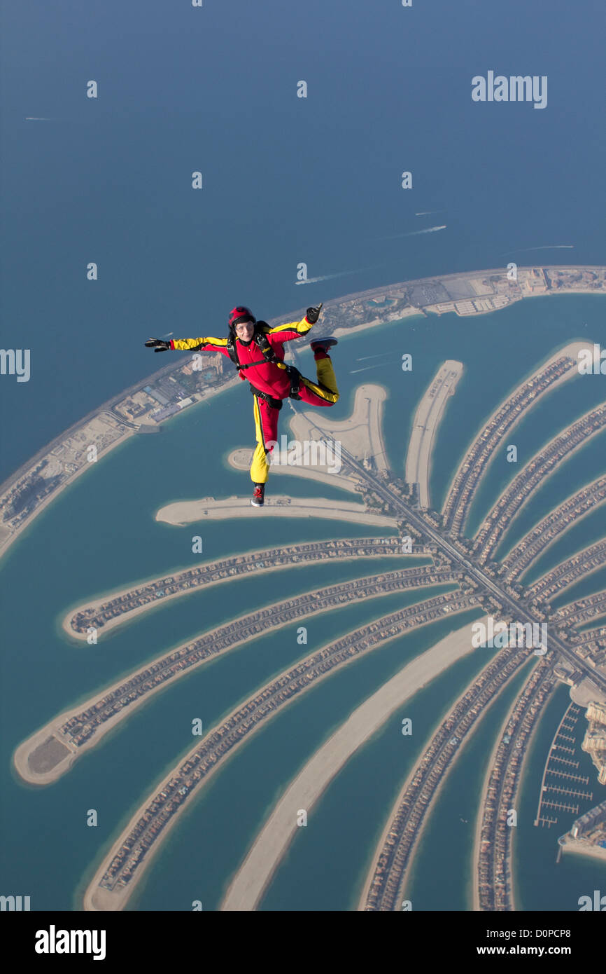Skydiver girl is flying free over the Dubai palm and performance a free style move. The scenery is perfect from this hight. Stock Photo