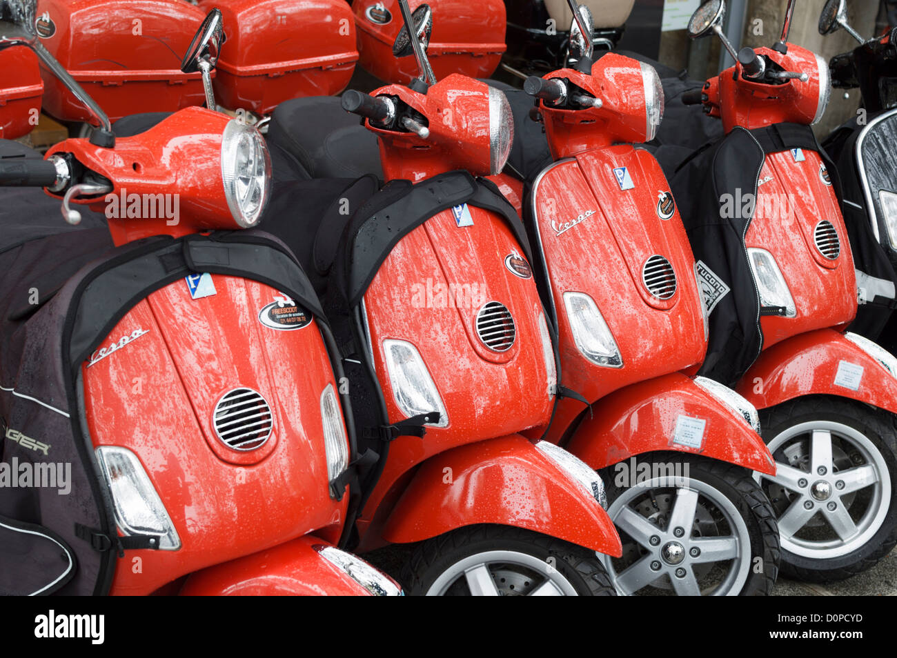 Paris, France: Red Piaggio Vespa motor scooters for hire - parked in a row outside a rental shop. Stock Photo
