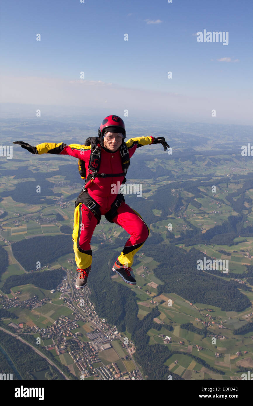 This skydiver is having fun and falling free in a sit position with 120mph speed over nice land scape. Stock Photo