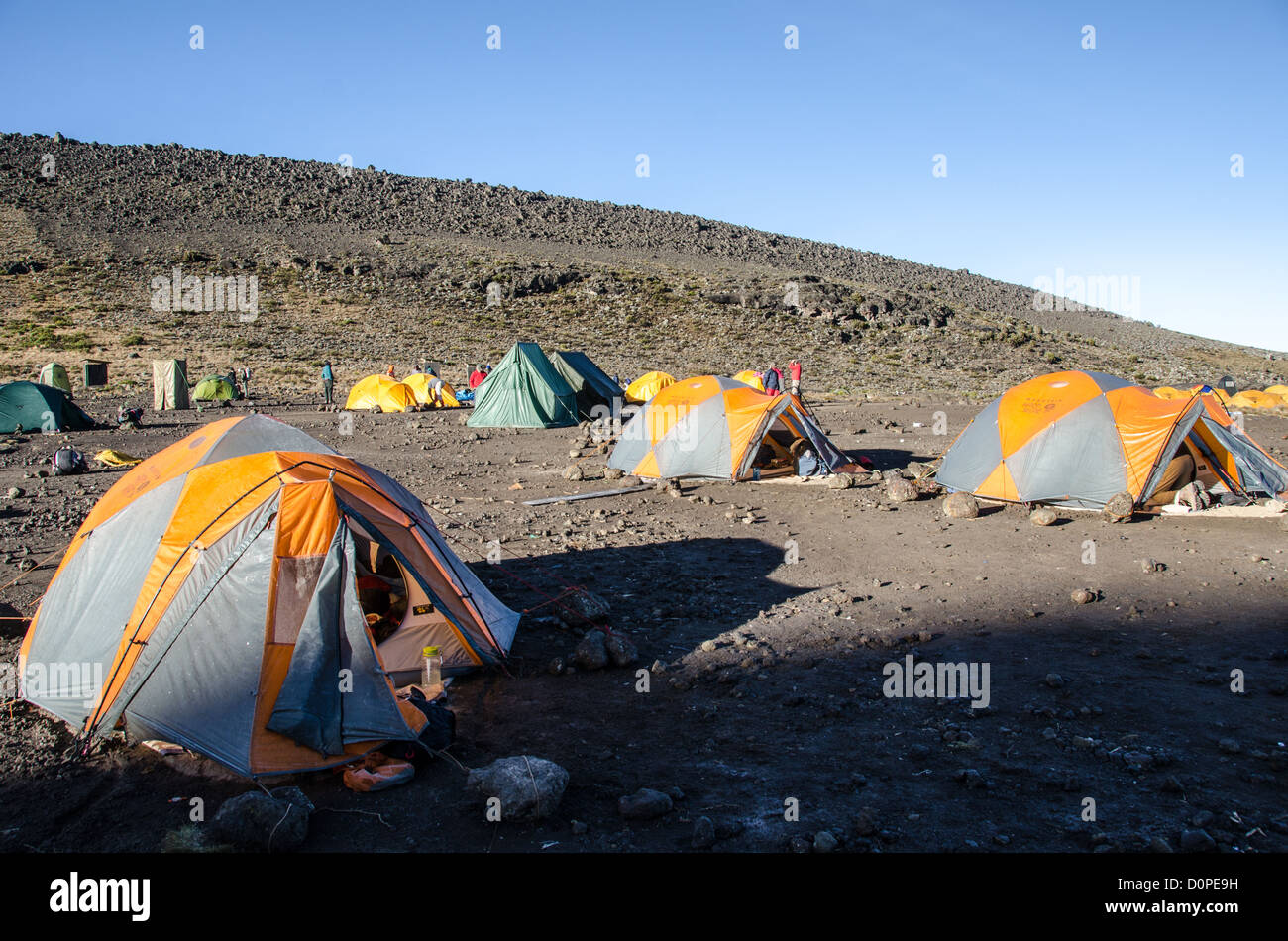 MOUNT KILIMANJARO, Tanzania — Tents are positioned at Moir Hut Camp, situated at 13,660 feet elevation on Mount Kilimanjaro's Lemosho Route. The camp serves as one of the designated stopping points for climbers ascending Africa's highest peak via the Lemosho approach. Mount Kilimanjaro, located in northern Tanzania near the Kenyan border, rises to 19,341 feet and attracts thousands of trekkers annually. The Lemosho Route is widely considered one of the more scenic approaches to the summit, typically taking seven to eight days to complete. Moir Hut Camp provides a crucial acclimatization stop f Stock Photo