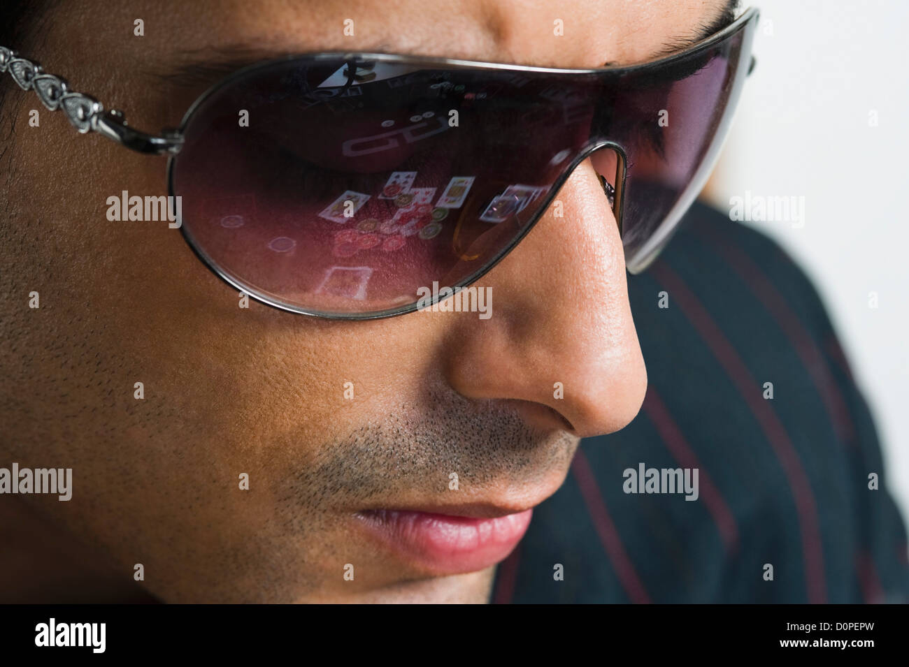 Reflections of playing cards and gambling chips in the goggles worn by a man in casino Stock Photo
