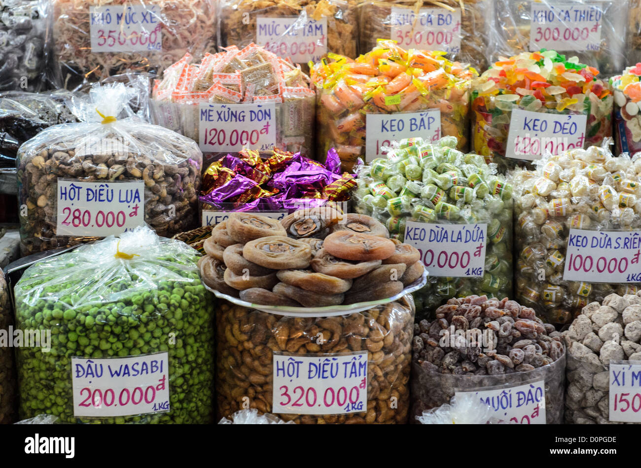HO CHI MINH CITY, Vietnam — Candy and snacks are displayed for sale with Vietnamese price labels at Ben Thanh Market. Ben Thanh Market is one of Ho Chi Minh City's most prominent marketplaces, serving as a major commercial hub in the city center. The market, originally built during the French colonial period, features hundreds of stalls selling food, spices, textiles and souvenirs. Located in District 1, Ben Thanh Market attracts both local shoppers and international visitors. The market operates as both a traditional Vietnamese marketplace and a popular tourist destination, remaining one of t Stock Photo