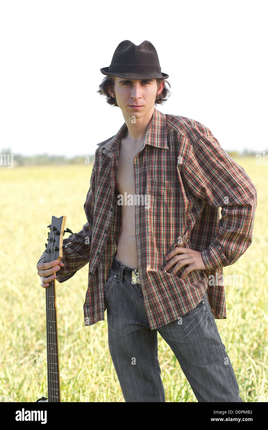 Young rocker posing with musical instrument outdoors at bright summer ...
