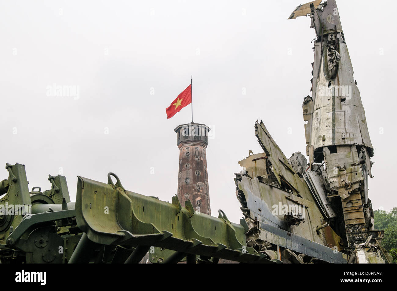 HANOI, Vietnam - Wreckage from the Vietnam War in front of the the Hanoi Flag Tribune at the Vietnam Military History Museum. The tower was built in the early 19th century (1805-1812) and stands 33.5 meters tall. A 54-step spiral staircase leads to the top, where there is a small viewing room. A national flag has flown atop the tower night and day since October 10, 1954, after the defeat of the French at Dien Bien Phu. The monument has been designated by the Ministry of Culture and Information as a National Cultural and Historic Relic. The museum was opened on July 17, 1956, two years after th Stock Photo
