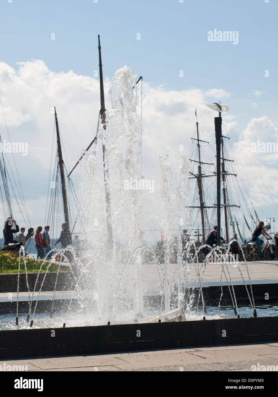 Fountain in Rådhusplassen, city hall square in Oslo Norway with people and sail boats rigs at the back Stock Photo