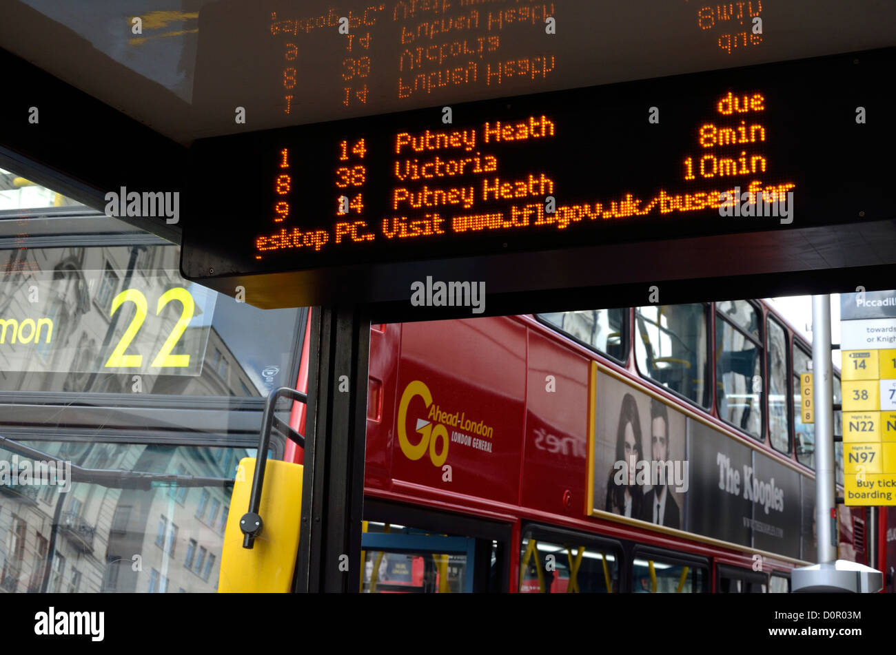 London, England, UK. Bus stop. Red double-decker and electronic sign giving bus times Stock Photo