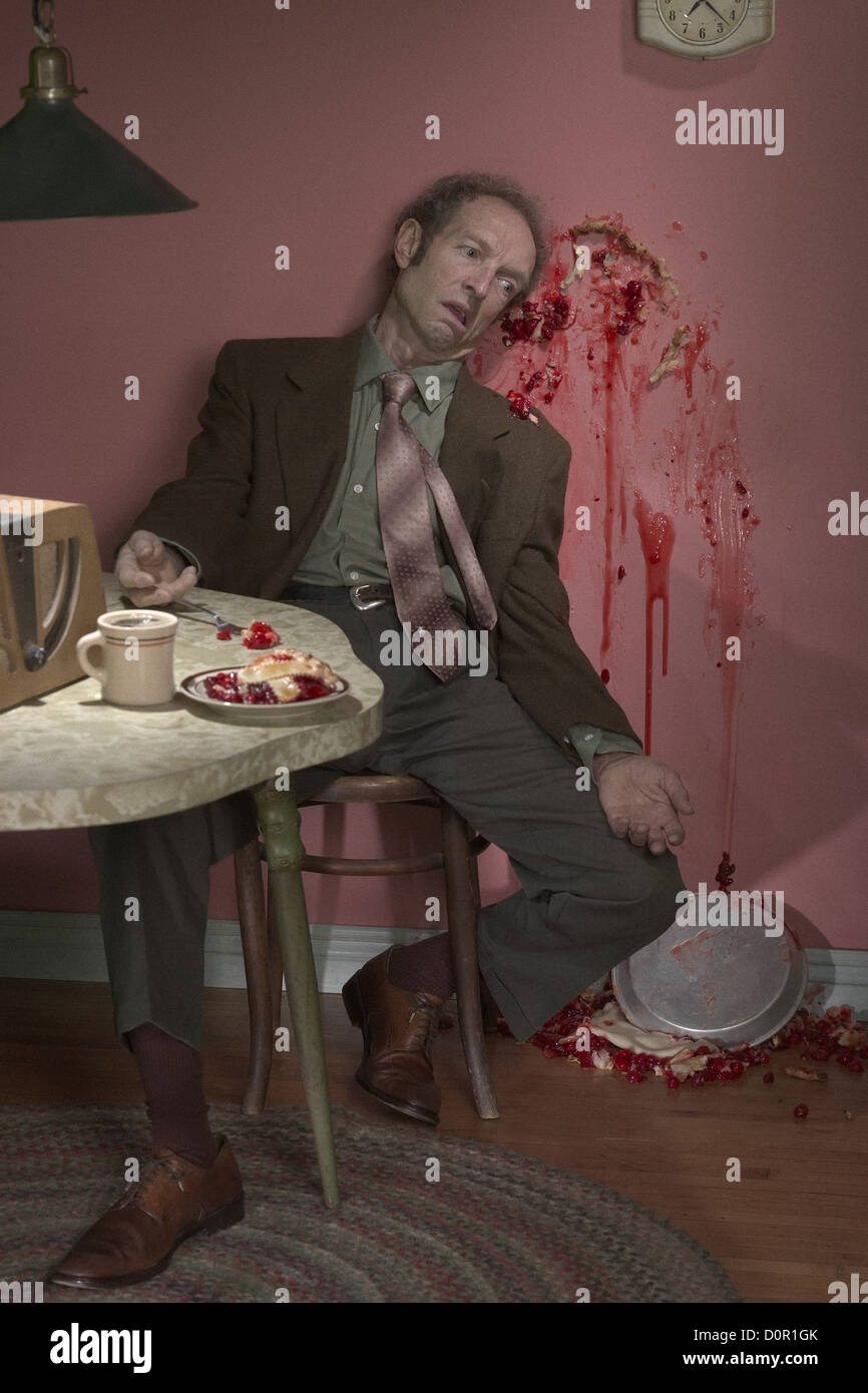 Retro looking crime scene with middle aged man, murdered by cherry pie Stock Photo