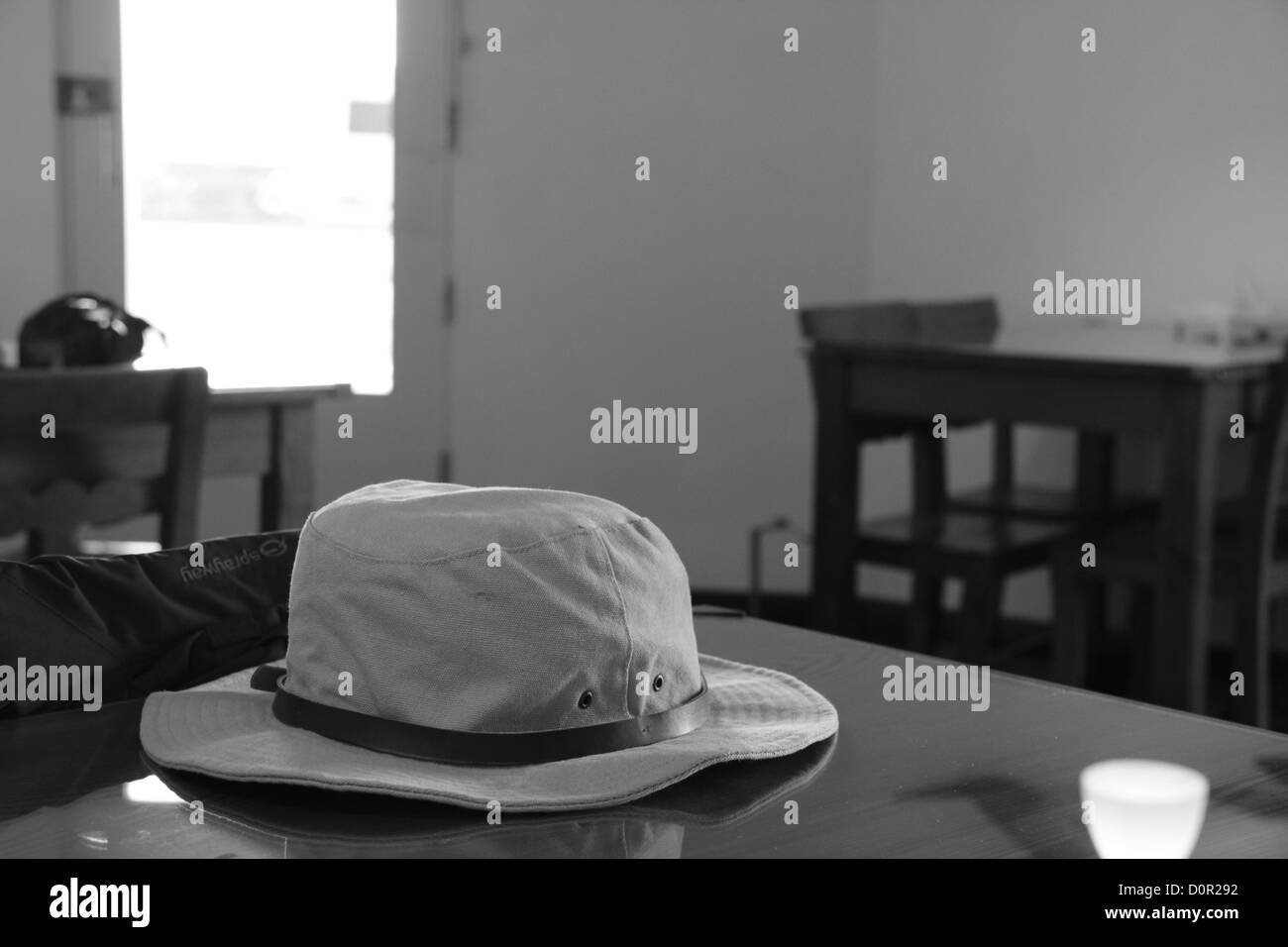 Black and white image of a hat on a table in a cafe Stock Photo