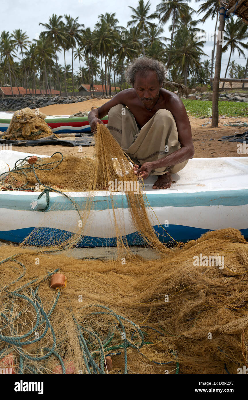 Sri Lanka fisherman repairing his fishing net while sitting on his