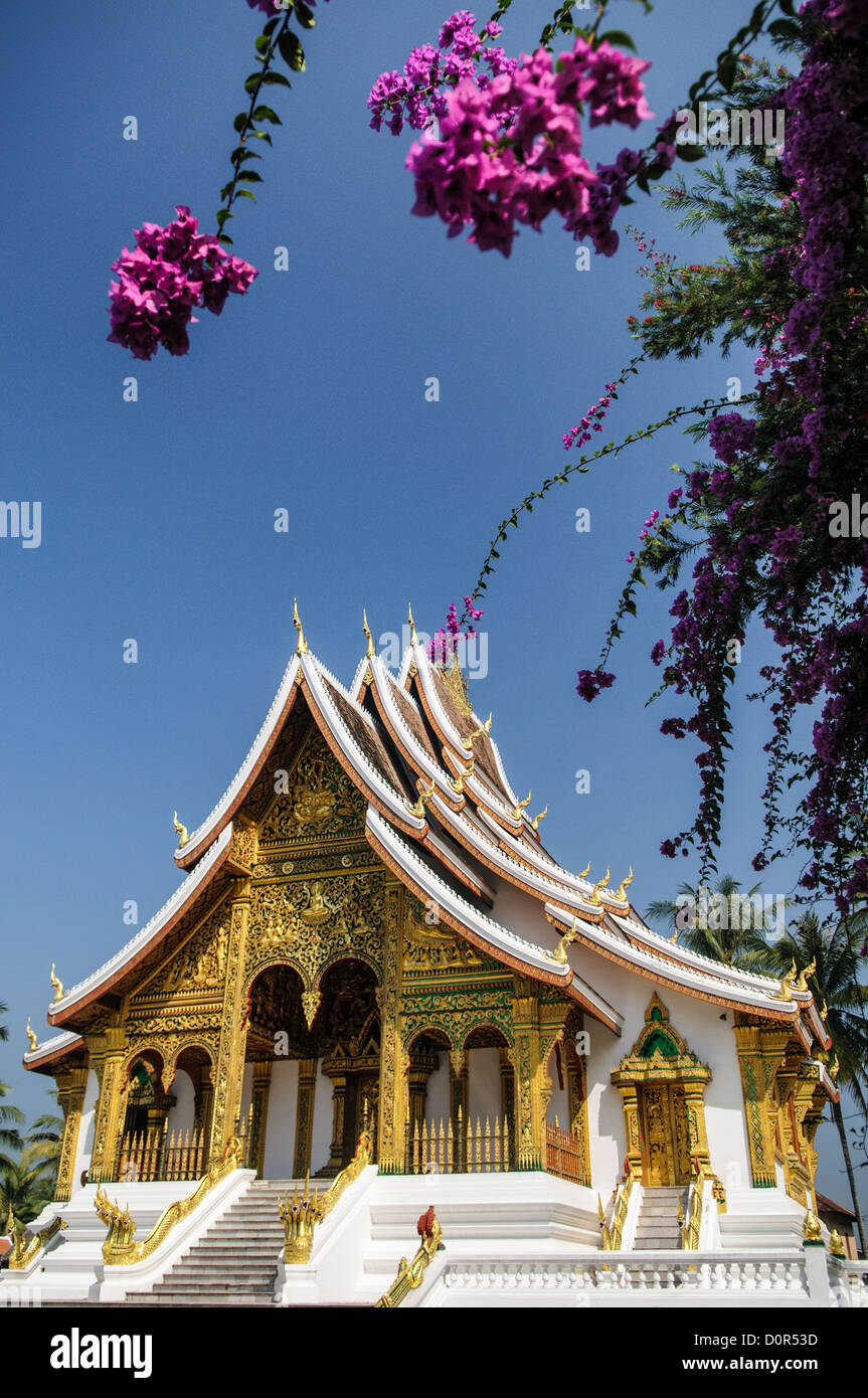 LUANG PRABANG, Laos - Haw Pha Bang (or Palace Chapel) building framed by purple flowers at the Royal Palace Museum in Luang Prabang, Laos. The chapel sits at the northeastern corner of the grounds. Construction started in 1963. Stock Photo