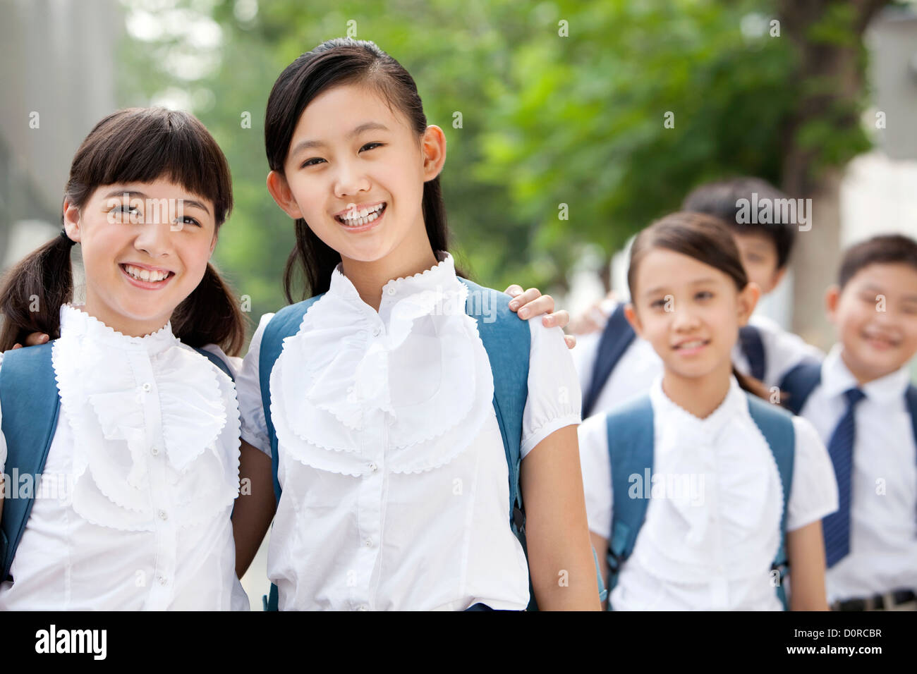 Happy schoolgirls in uniform with friends outdoors Stock Photo - Alamy