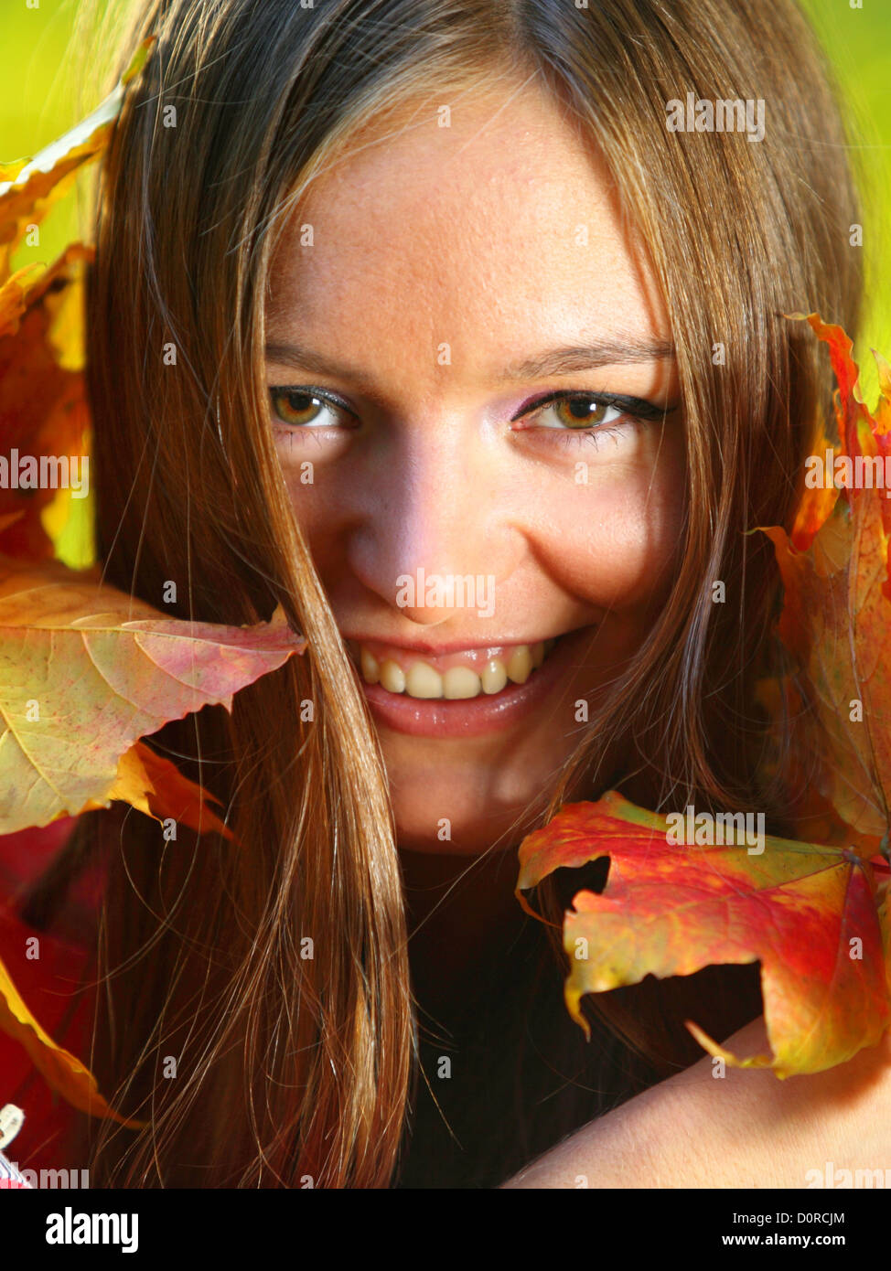 Young woman with autumn leaves in hand and fall yellow maple garden ...