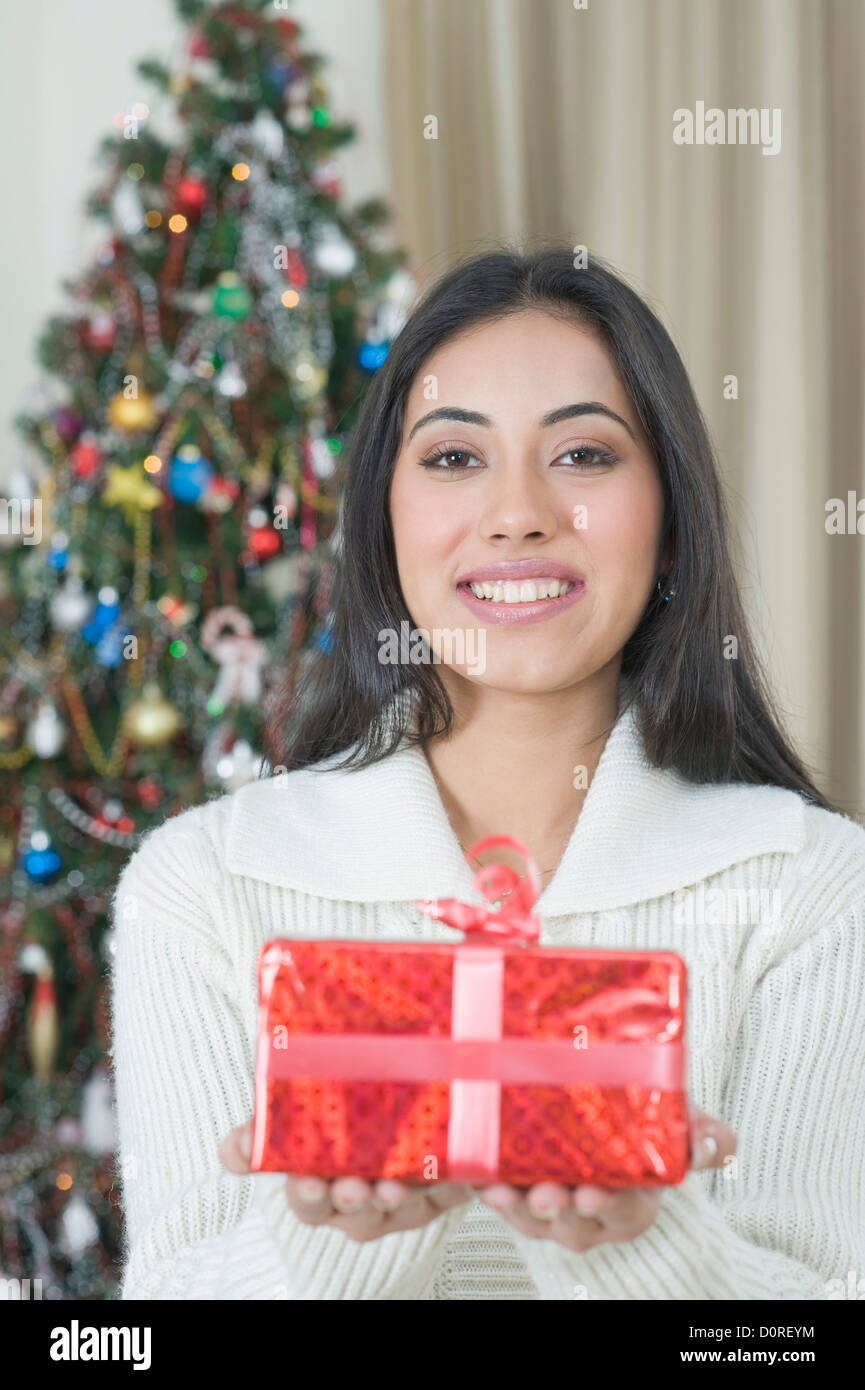 Woman holding a Christmas present and smiling Stock Photo - Alamy
