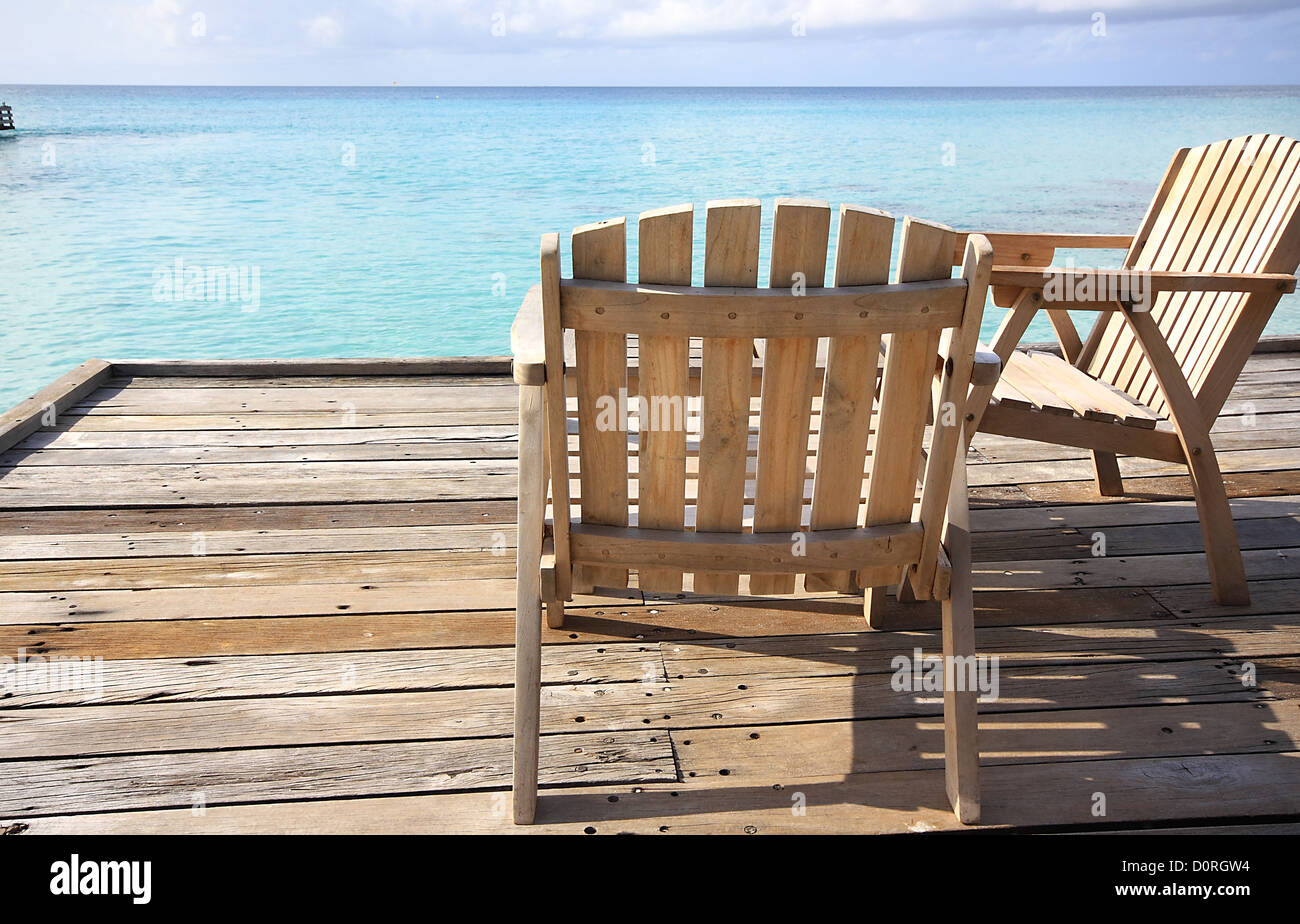 Two wooden chairs and a table in the Maldives overlooking the Indian ...