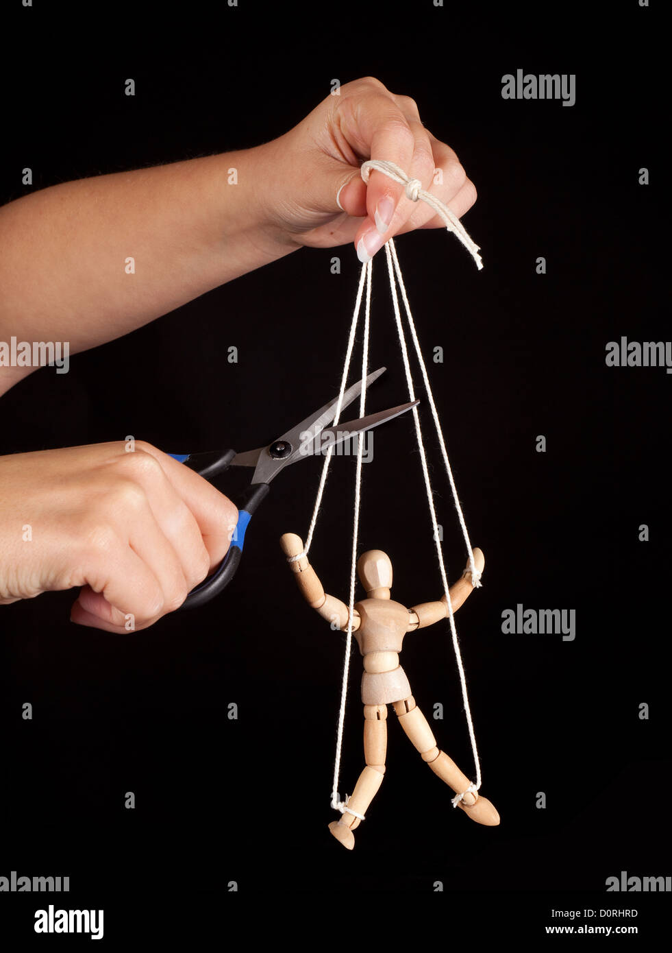 Hand cutting the strings of a puppet, giving it freedom Stock Photo