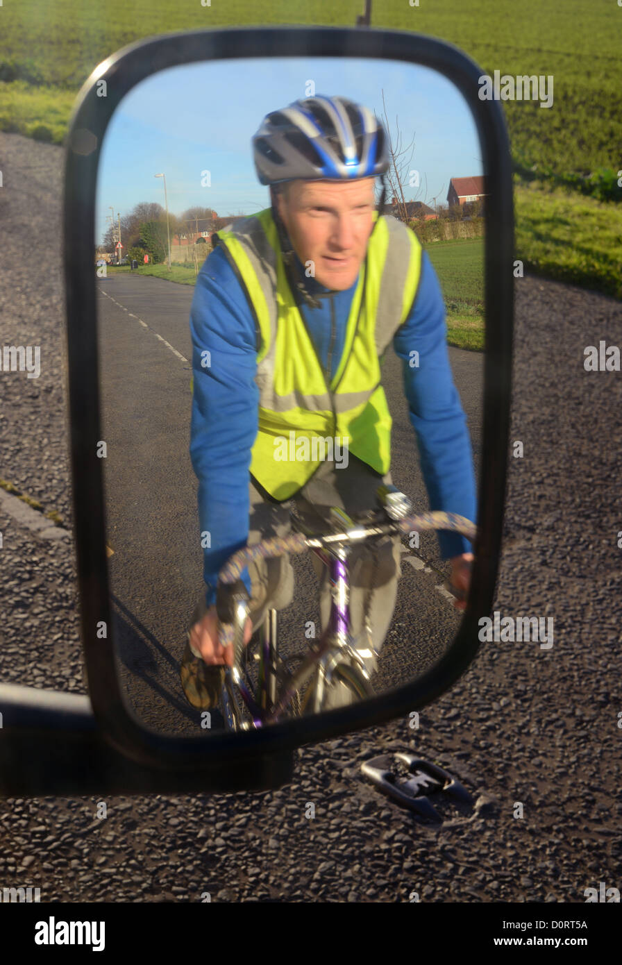 cyclist wearing high visibility clothing refelected in vehicle wing mirror on road near Leeds United Kingdom Stock Photo