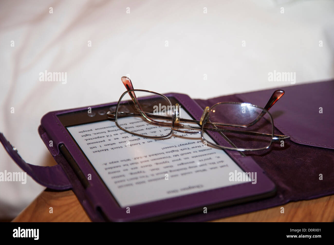 Night time reading, reading in bed. electronic book ereader kindle with reading glasses on bed