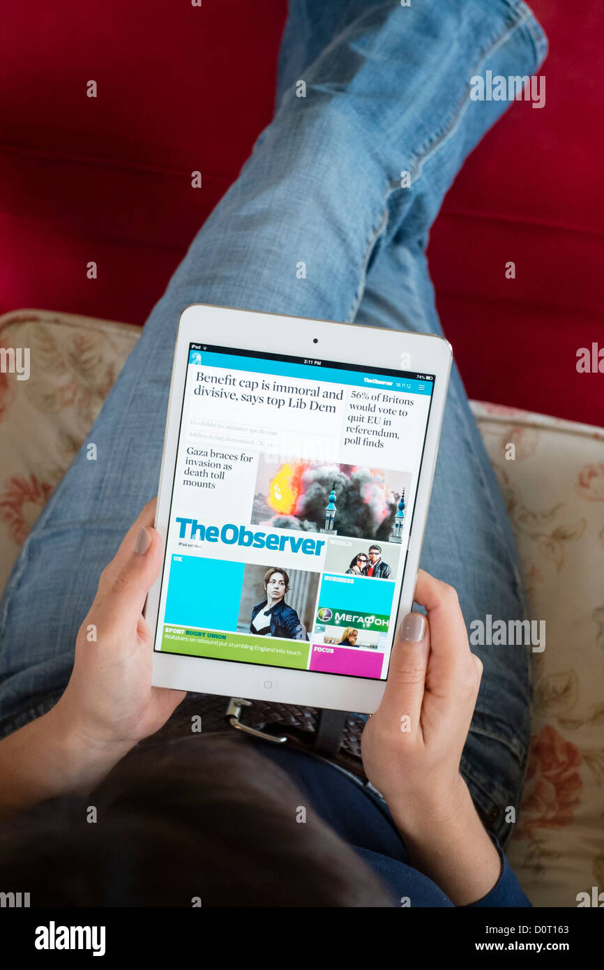 Woman using Kindle application of read digital edition of The  Observer newspaper  on an iPad mini tablet computer Stock Photo