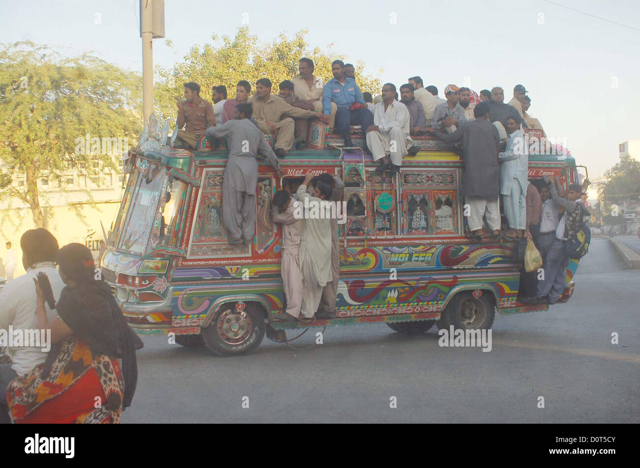 Passengers travel on an overload bus due to non-availability  of passenger buses in Karachi on Friday, November 30, 2012. Shortage of transportation  observed in Karachi due to unofficial strike call by the CNG Pumps owners against highly-  unreasonable retail price of CNG that is causing them massive financial losses. Stock Photo